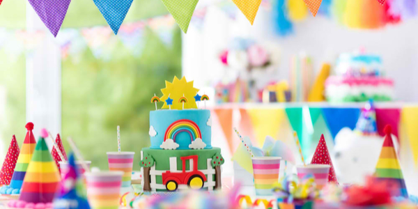 Kids birthday party decoration. Colorful cake with candles. Farm and transportation theme boys party. Decorated table for child birthday celebration. Rainbow cake for little boy. Balloons and banners.
